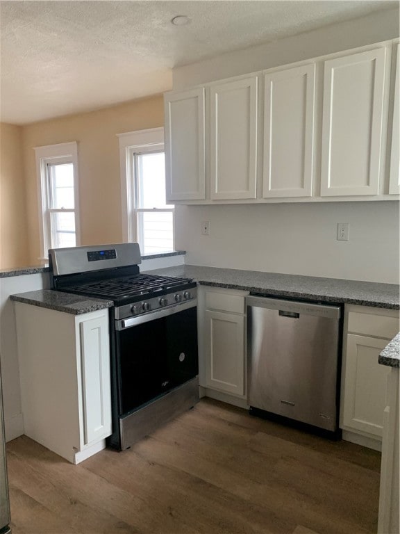 kitchen featuring white cabinets, a textured ceiling, stainless steel appliances, and hardwood / wood-style flooring