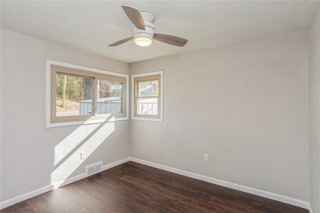 spare room with dark hardwood / wood-style floors, a wealth of natural light, and ceiling fan