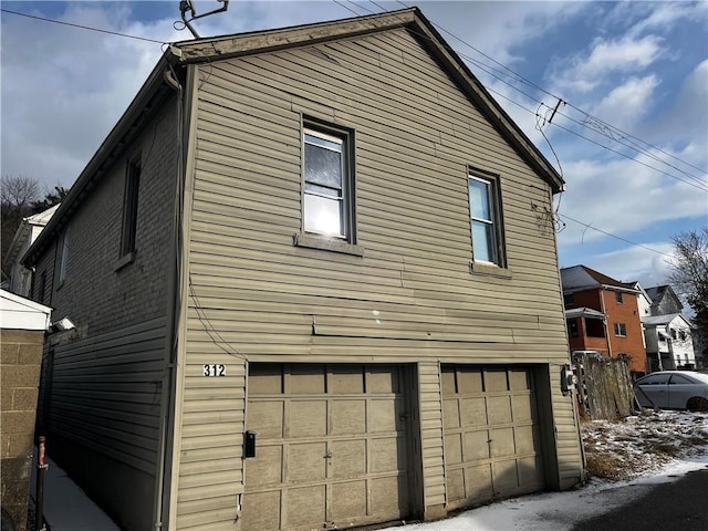 view of side of home featuring an attached garage and brick siding