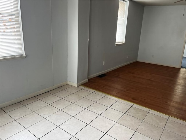 empty room with light wood-type flooring, visible vents, and baseboards