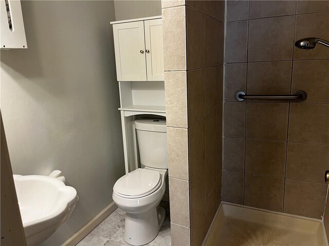 full bathroom featuring a stall shower, baseboards, and toilet