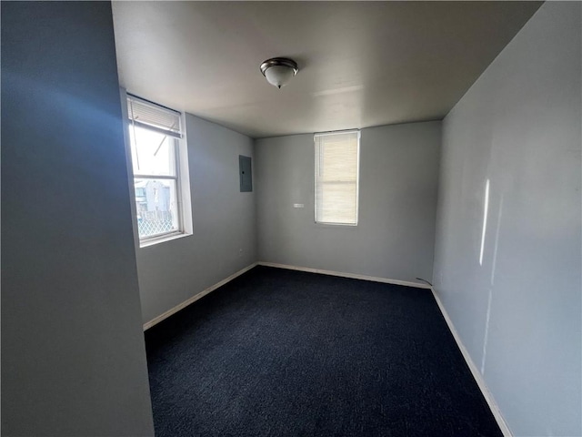 spare room with baseboards, electric panel, and dark carpet