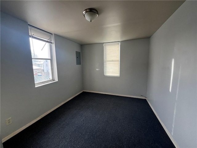 carpeted empty room with electric panel and baseboards