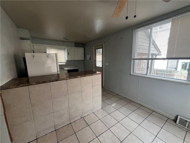 kitchen featuring freestanding refrigerator, visible vents, white cabinets, and dark countertops