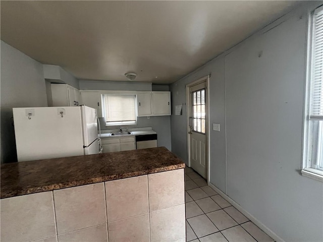 kitchen with a sink, white cabinets, freestanding refrigerator, dishwasher, and dark countertops