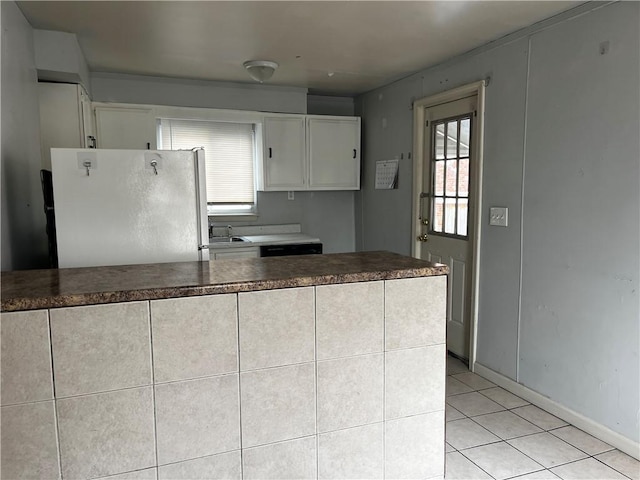 kitchen featuring dark countertops, light tile patterned floors, white cabinets, and freestanding refrigerator