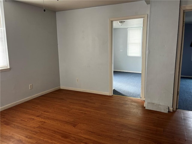 spare room featuring dark wood-style flooring and baseboards