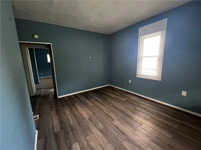empty room featuring dark wood finished floors and baseboards