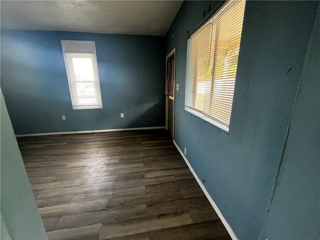 spare room with baseboards and wood finished floors