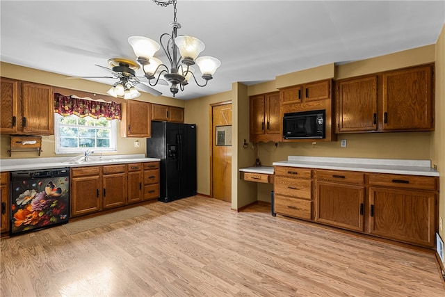 kitchen with pendant lighting, black appliances, ceiling fan with notable chandelier, and light wood-type flooring