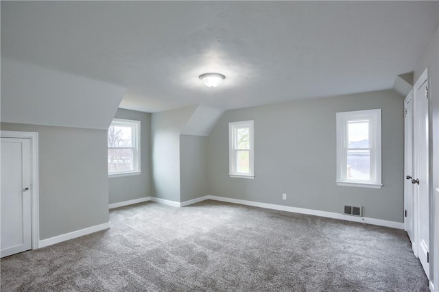 bonus room with light carpet and vaulted ceiling