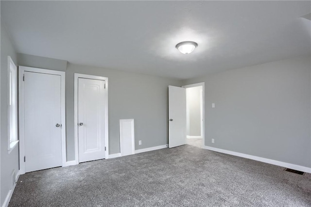 unfurnished bedroom with multiple closets and carpet floors