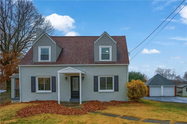 cape cod home with an outbuilding, a front yard, and a garage