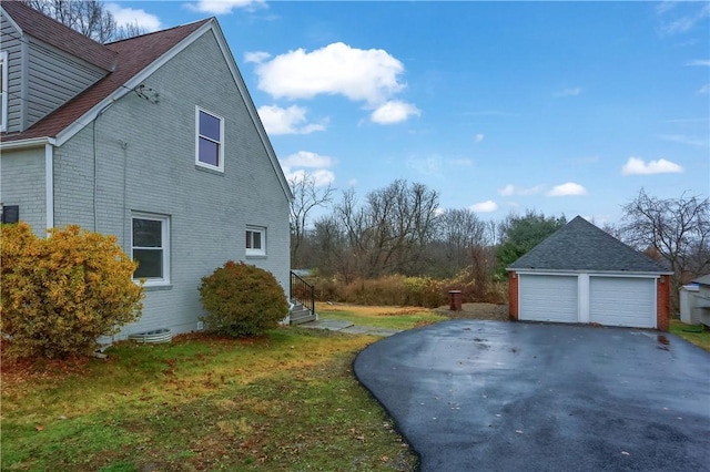 view of side of home with a garage, a yard, and an outbuilding