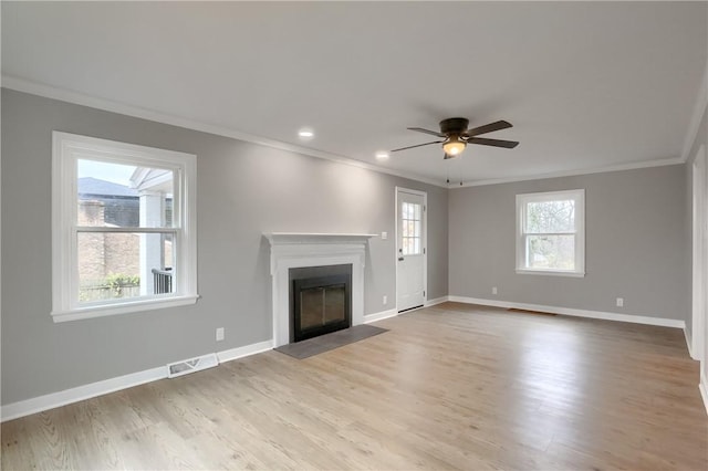 unfurnished living room featuring ceiling fan, a healthy amount of sunlight, light hardwood / wood-style floors, and ornamental molding