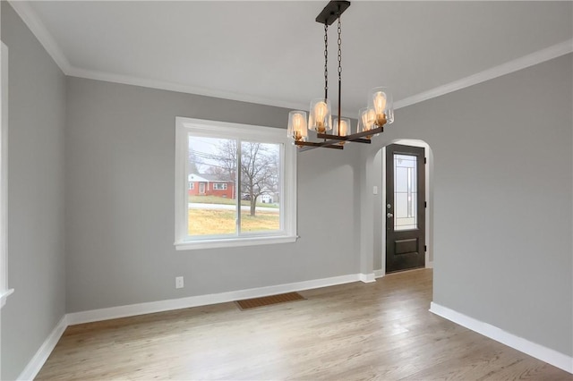 unfurnished dining area with an inviting chandelier, wood-type flooring, and ornamental molding