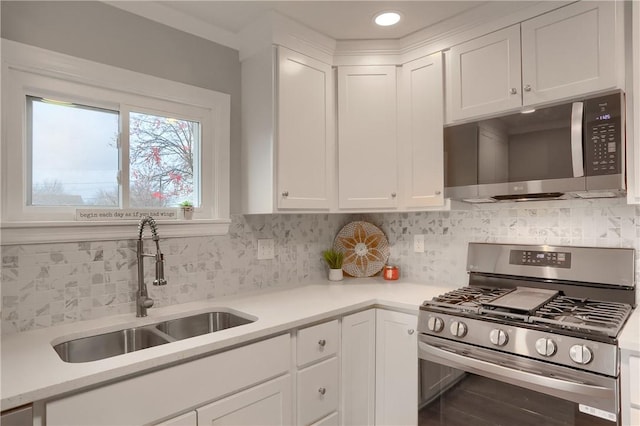 kitchen featuring backsplash, white cabinetry, sink, and appliances with stainless steel finishes