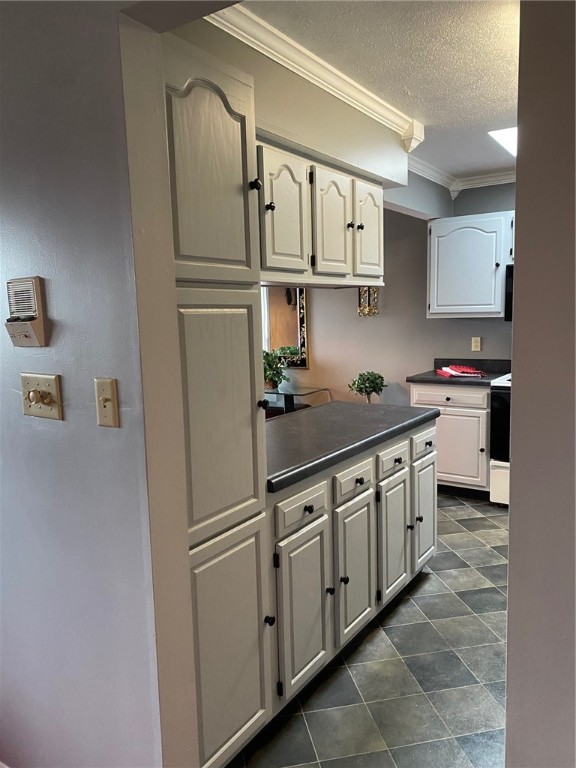 kitchen with range, white cabinets, a textured ceiling, and ornamental molding