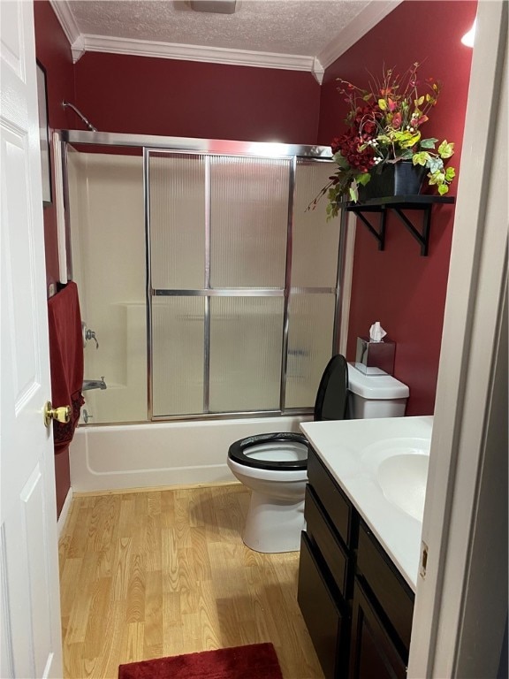 full bathroom with hardwood / wood-style floors, a textured ceiling, shower / bath combination with glass door, vanity, and ornamental molding