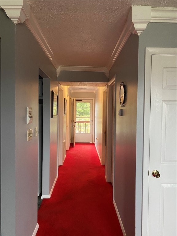 hallway featuring a textured ceiling, dark carpet, and crown molding