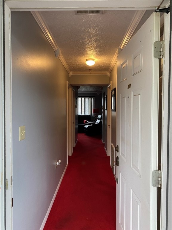 corridor featuring a textured ceiling, dark carpet, and crown molding