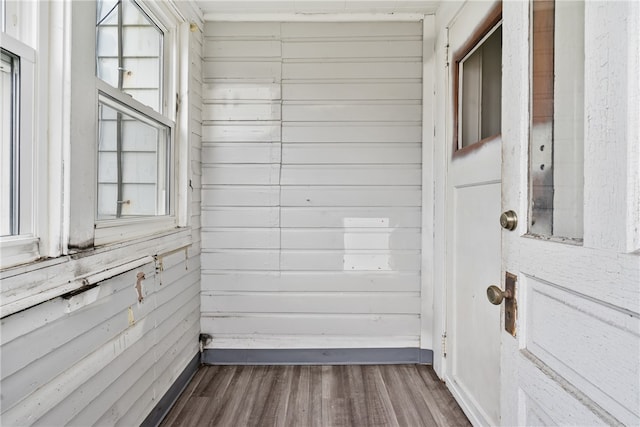 interior space with plenty of natural light, dark wood-type flooring, and wooden walls