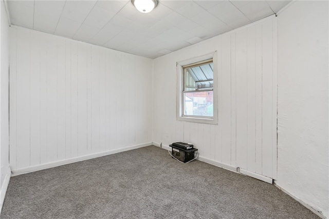 unfurnished room with carpet flooring and wood walls