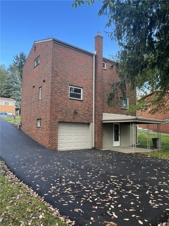 221 Sharon Dr, Forest Hills Boro, PA 15221 - view of side of home with brick siding, asphalt driveway, a garage, and a chimney