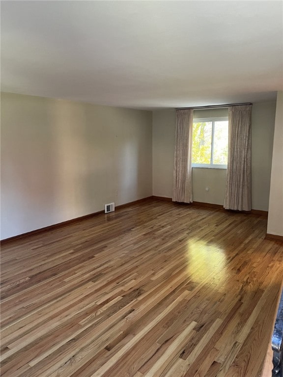 empty room with visible vents, baseboards, and wood finished floors