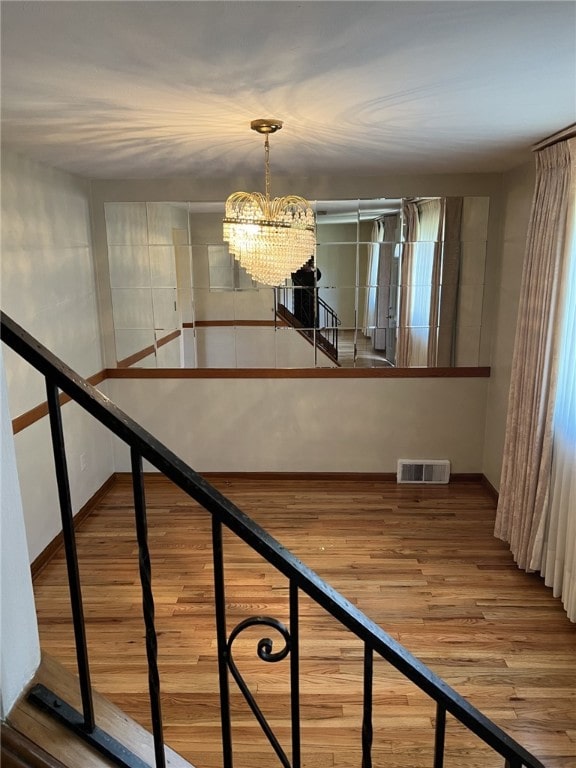 staircase with wood-type flooring and a notable chandelier