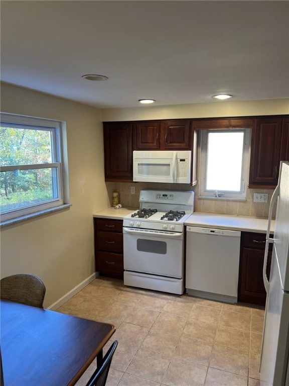 kitchen with light countertops, white appliances, dark brown cabinets, and plenty of natural light