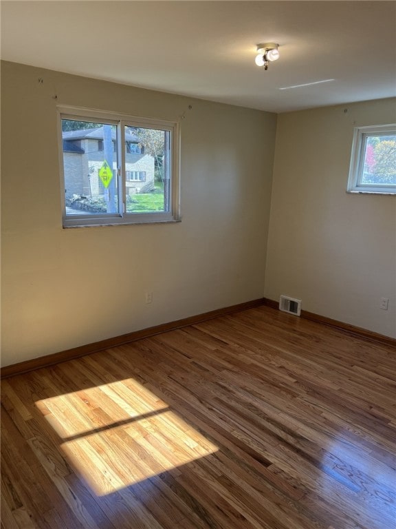 empty room featuring visible vents, baseboards, and wood finished floors