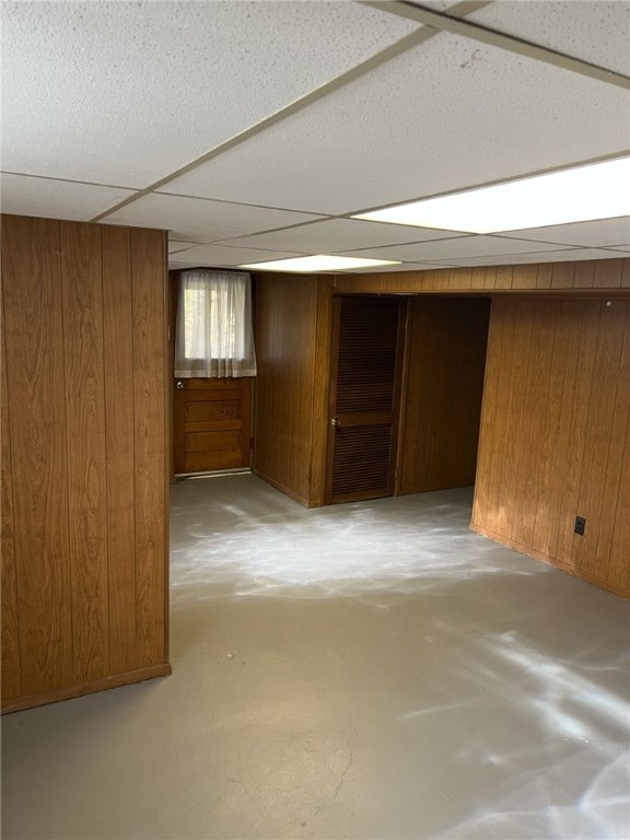 basement with a paneled ceiling and wooden walls