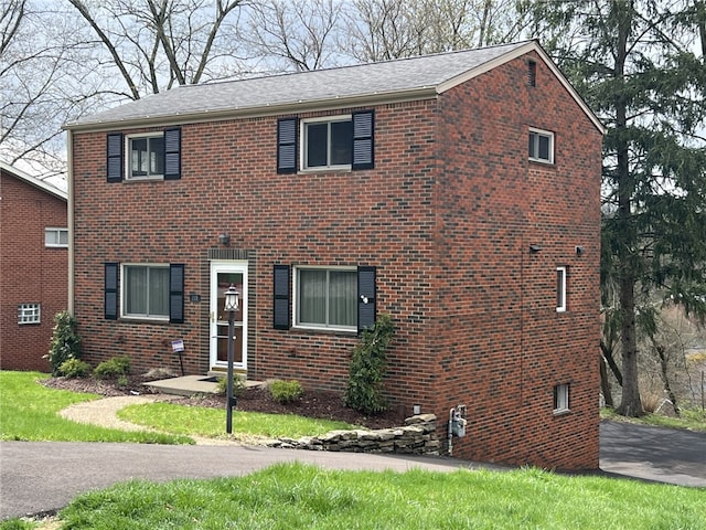 view of front facade with roof with shingles and brick siding