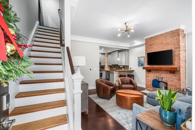 interior space featuring a chandelier, dark hardwood / wood-style flooring, ornamental molding, and a brick fireplace