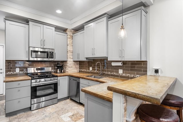 kitchen with stainless steel appliances, a kitchen breakfast bar, kitchen peninsula, pendant lighting, and gray cabinets