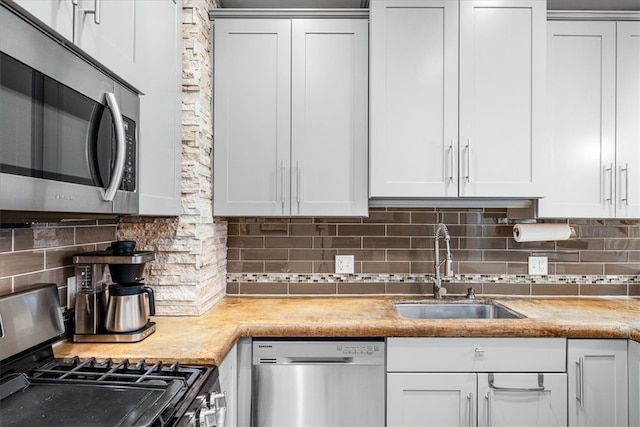 kitchen featuring decorative backsplash, appliances with stainless steel finishes, white cabinets, and sink