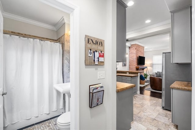 bathroom featuring toilet, shower / bath combo with shower curtain, and ornamental molding