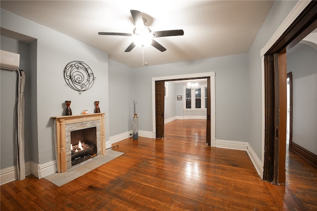 unfurnished living room featuring a wall mounted air conditioner, ceiling fan, dark wood-type flooring, and a premium fireplace