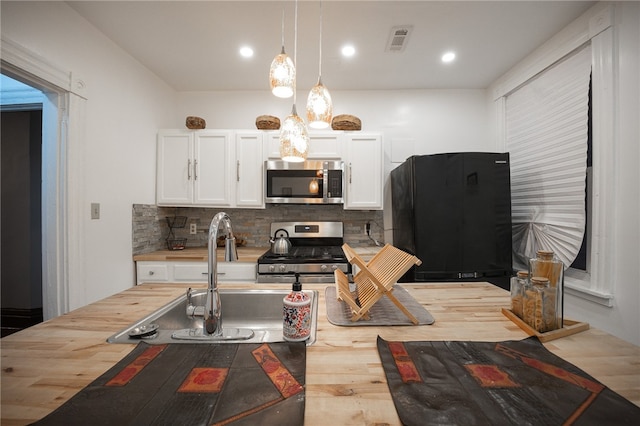 kitchen featuring backsplash, white cabinetry, hanging light fixtures, and appliances with stainless steel finishes