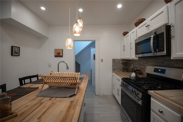 kitchen with white cabinetry, hanging light fixtures, stainless steel appliances, wooden counters, and backsplash