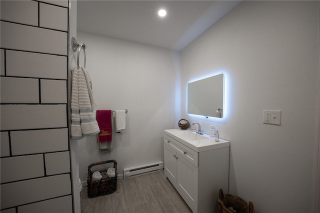 bathroom with hardwood / wood-style floors, vanity, lofted ceiling, and baseboard heating