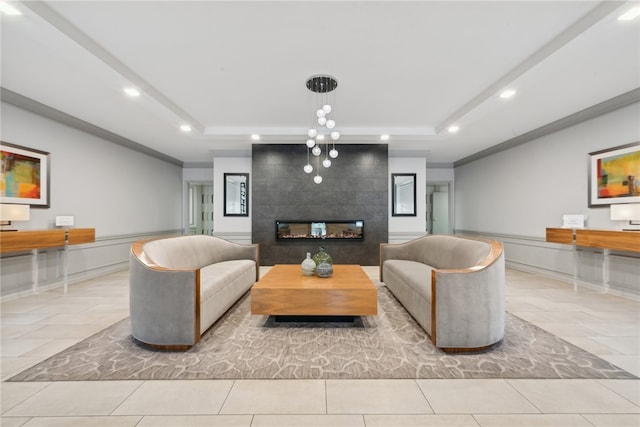 living room featuring a tiled fireplace, crown molding, and a tray ceiling