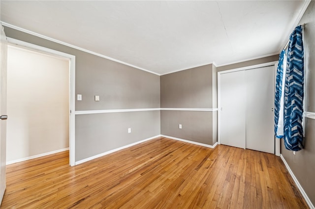 unfurnished bedroom with light hardwood / wood-style floors, a closet, and crown molding