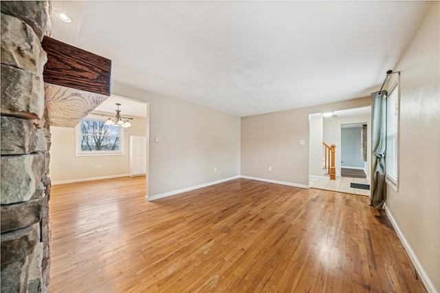 unfurnished living room featuring an inviting chandelier and light wood-type flooring