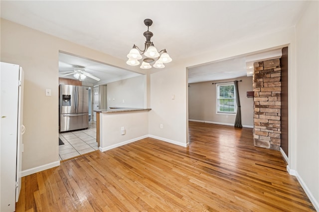 interior space with ceiling fan with notable chandelier and light hardwood / wood-style floors