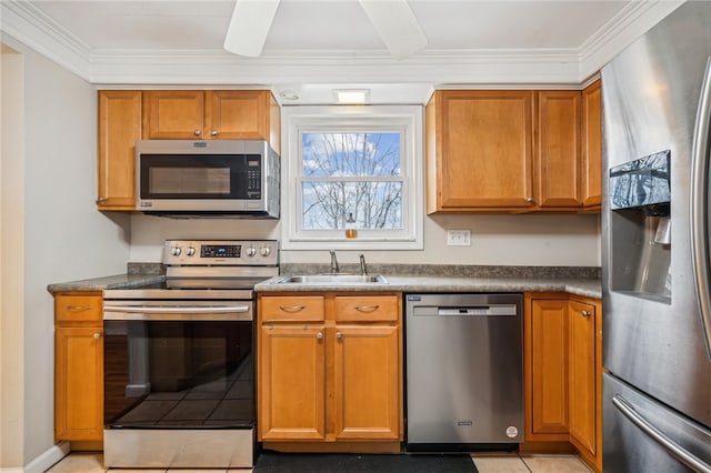 kitchen featuring light tile patterned floors, stainless steel appliances, ornamental molding, and sink