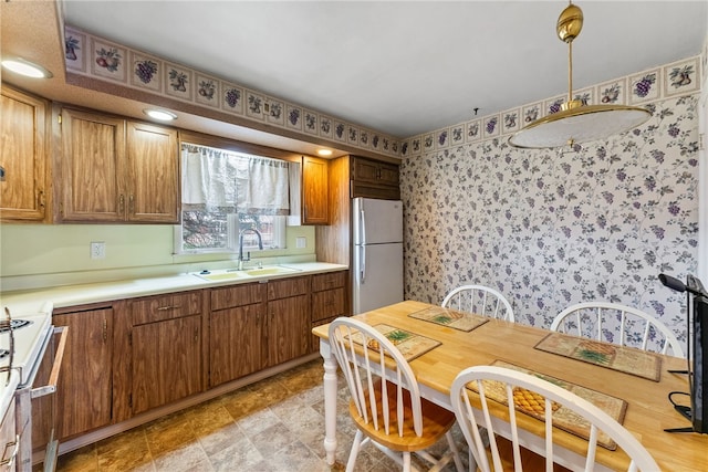 kitchen with white refrigerator, stove, sink, and hanging light fixtures