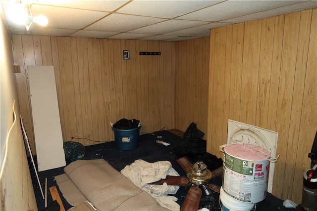 interior space with a paneled ceiling and wooden walls