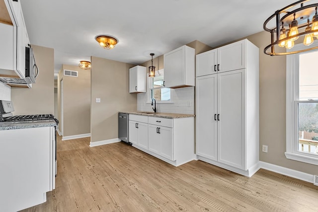 kitchen with pendant lighting, light hardwood / wood-style floors, white cabinetry, and appliances with stainless steel finishes